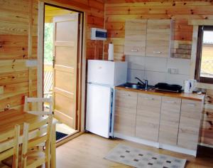 eine Küche mit einem weißen Kühlschrank in einer Hütte in der Unterkunft Domki LaPlata na Kaszubach in Wiele