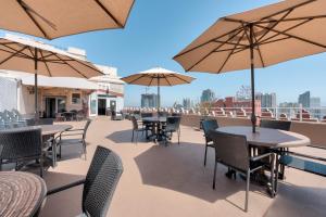 a patio with tables and chairs and umbrellas on a roof at Gaslamp Plaza Suites in San Diego