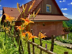 ein Haus mit rotem Dach und einem Zaun mit Blumen in der Unterkunft Kopanický dvor in Hodruša
