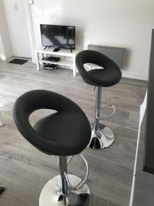 a room with two black chairs and a television at Studio 50m Plage in Dunkerque