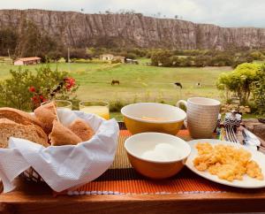 a table with a plate of bread and two bowls and cups at Casa en el Árbol in Suesca