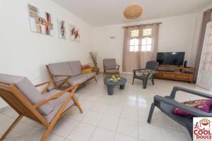a living room with chairs and a flat screen tv at Kouleur Karayib in Le Gosier