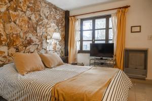 a bedroom with a large bed and a stone wall at Posada Del Fin Del Mundo in Ushuaia