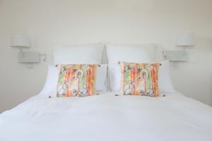a bedroom with a white bed with two pillows at Villa Clarisse in Deauville