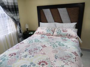 ein Bett mit einer rosa und weißen Bettdecke und Kissen in der Unterkunft LPM Guest in Pretoria