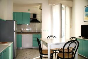 a kitchen with green cabinets and a white table and chairs at Residence Le Vele in Cattolica