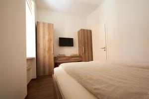 a white bedroom with a bed and a tv at Central Inn Apartments Sarajevo in Sarajevo