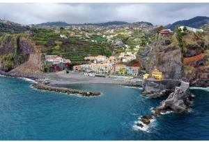 Een luchtfoto van een strand met een stadje op een heuvel. bij Apartamentos Villa in Ponta do Sol