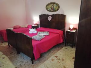 a bedroom with two beds with pink sheets and a mirror at Casa della nonna in Riposto