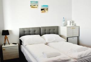 Una cama con sábanas blancas y almohadas. en Zakotwiczeni, en Rewa