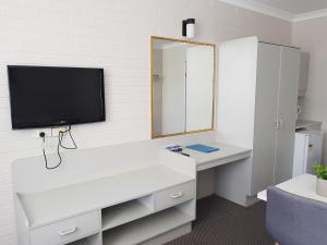 a bathroom with a sink, mirror and a television at Seabreeze Beach Hotel in South West Rocks