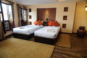una camera da letto con due letti e un muro di mattoni di Thagu Chhen, a Boutique Hotel a Bhaktapur