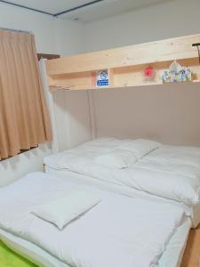 2 camas en una habitación con sábanas blancas en M's Kanazawa en Kanazawa