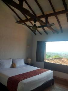 a bedroom with a bed and a large window at La Loma Hotel Barichara in Barichara