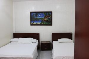 Habitación con 2 camas y una foto en la pared. en Aparta Hotel Puerto Nuevo, en Barrancabermeja