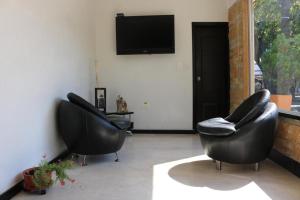 two black chairs in a living room with a tv at Aparta Hotel Puerto Nuevo in Barrancabermeja