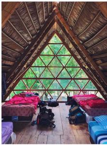 a room with three beds in a wooden ceiling at Pachamaya River Hostel in Lanquín