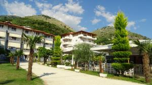 a building with palm trees in front of a mountain at Hotel Beach Restaurant Fabio in Borsh