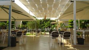 a patio with white chairs and tables and umbrellas at Hotel Beach Restaurant Fabio in Borsh