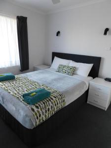 a bedroom with a large bed with two towels on it at Merimbula Lake Apartments in Merimbula