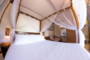 巴拉格兰德Luar do Leão Bungalow的卧室里有一张带顶篷的白色床