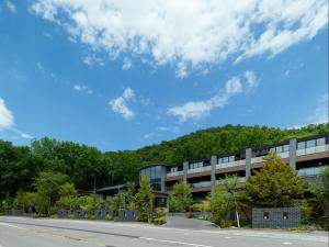 un immeuble de bureaux avec une montagne en arrière-plan dans l'établissement Lake Shikotsu Tsuruga Bessou AO no ZA, à Chitose