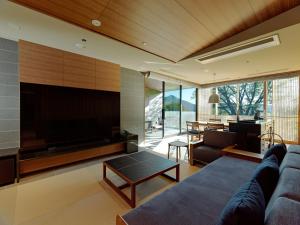 a living room with a couch and a large television at Lake Shikotsu Tsuruga Bessou AO no ZA in Chitose