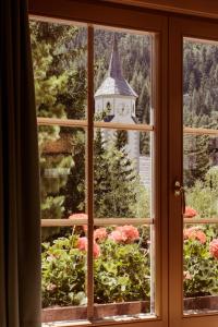 a window with a view of a clock tower at Berghotel Ladinia in Corvara in Badia