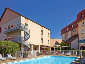 a hotel with a swimming pool in front of a building at ibis Beaune Centre in Beaune