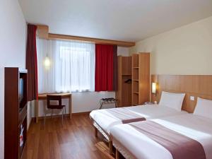 ein Hotelzimmer mit einem großen Bett und einem TV in der Unterkunft Ibis Kraków Stare Miasto in Krakau