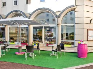 ein Restaurant mit Stühlen, Tischen und einem Sonnenschirm in der Unterkunft ibis Styles Strasbourg Stade de la Meinau in Straßburg