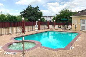 a swimming pool in a yard with a fence at Comfort Suites Texas Avenue in College Station