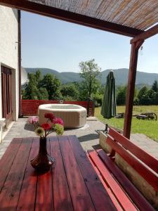 a wooden table with a vase of flowers on a patio at Holiday Home Lipa in Vrbovsko