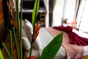 a flower in a vase in front of a bed at Rice Barn And Rooms in Hang Dong