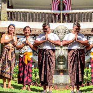 un grupo de personas de pie frente a una estatua en Hill Dance Bali American Hotel, en Jimbaran