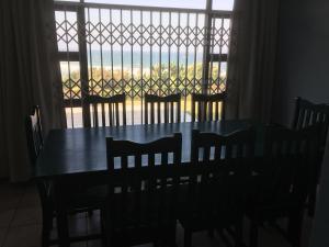 Una mesa de comedor con sillas y una gran ventana. en Go Slow, en Port Shepstone