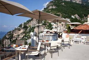 a patio area with chairs, tables and umbrellas at Hotel Punta Regina in Positano