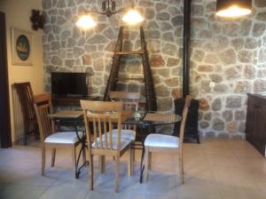 a table and chairs in a room with a stone wall at Ktima Nafsika - First-floor luxury apartment in majestic estate in Rozaíika