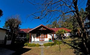 uma casa branca com um telhado vermelho em Hotel Clouds End Villa Cottages em Dharamshala