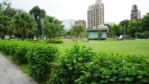 台北的住宿－千慧商務旅館，一座公园,里面是绿色的灌木丛和建筑