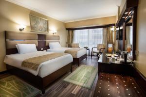 a hotel room with two beds and a desk at Pyramisa Suites Hotel Cairo in Cairo