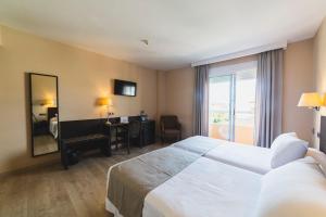 a hotel room with a bed and a desk and a window at Hotel Cristina in Los Alcázares