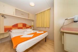a bedroom with a large bed with an orange blanket at Diana & Josip Mobile Homes in Biograd na Moru