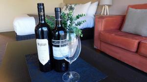 佩諾拉的住宿－亞歷山大卡梅隆套房汽車旅館，客厅桌子上放着两瓶葡萄酒