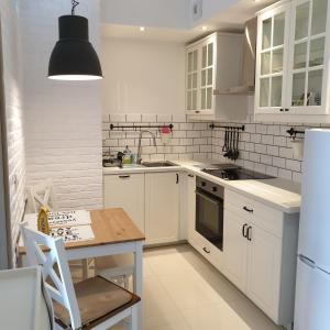 een keuken met witte kasten, een tafel en een koelkast bij Apartament Calamo Park in Olsztyn