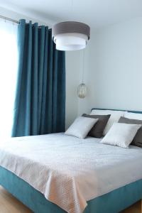 Un dormitorio con una cama grande con cortinas azules. en M&K Apartamenty-Amber, en Gdansk