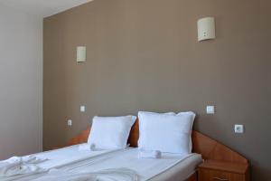 uma cama com lençóis brancos e duas almofadas em Hotel Milan em Primorsko