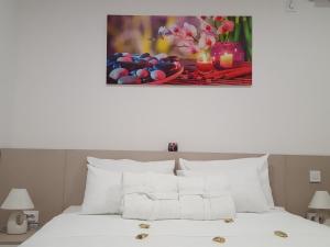 a bedroom with a white bed with a painting on the wall at Guesthouse Laterna in Herceg-Novi