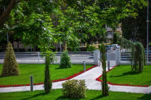 un parque con flores rojas, árboles y una acera en Hotel Meduza Estival en Olimp