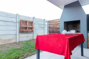 einen Tisch mit einem roten Tischtuch auf einer Terrasse in der Unterkunft Memories Self-Catering at 5 on Smith in Oudtshoorn
